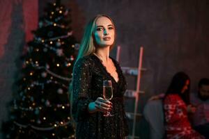 Beautiful young woman with glass of champagne at Christmas party photo