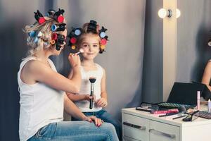 madre y su niño niña son haciendo tu maquillaje y teniendo divertido foto