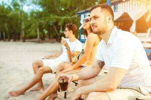 Young people enjoying summer vacation sunbathing drinking at beach bar photo