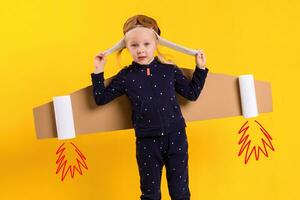 un pequeño niño niña es vistiendo hecho en casa cartulina volador alas, fingiendo a ser un piloto para un artesanía, imaginación o exploración concepto. foto