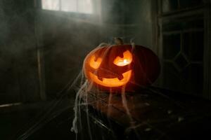 Halloween pumpkin head jack o lantern with spider web in dark room. photo