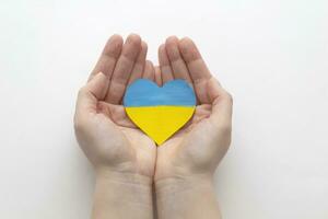 The concept of ending the war in Ukraine. heart in the colors of the flag of Ukraine in female hands. photo