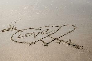 drawing in sand in form of two hearts and inscription love photo