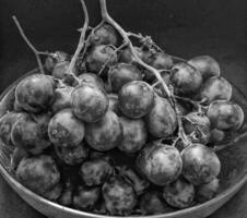 Black and white photo with an abstract photo concept for the background, Portrait a sprig of grapes or vitis vinifera in the bowl