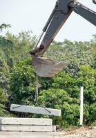 Backhoe is working by lifting cement bloc photo