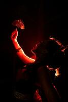 silueta de un hembra bailarín participación joyería en el medio de el quietud de el noche con rojo ligero foto