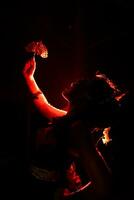 the silhouette of a female dancer holding jewelry that looks like a reflection reflecting in the dim light photo