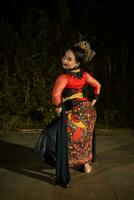 a Vietnamese dancer wearing a red costume and gold jewelry on stage at night photo