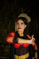 un indonesio bailarín en rojo ropa y un negro bufanda poses con muy Rizado y hermosa dedos foto