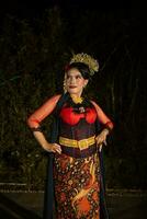 a Vietnamese dancer wearing a red costume and gold jewelry on stage at night photo