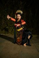 an Asian dancer dancing on her knees while wearing a black and luxurious costume in front of the audience photo