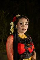 An Indonesian dancer in a gold and red costume stands very gracefully photo