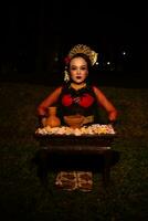 wide shot of an Asian girl in traditional clothes sitting in a forest with a table full of flowers photo