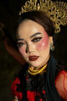 un asiático mujer con maquillaje en su cara y vistiendo un negro chal mientras bailando foto