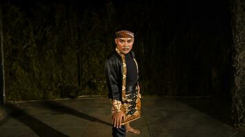 an Indonesian man dances with determination and skill while wearing a black costume on stage photo