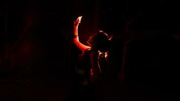 silhouette of a female dancer holding jewelry in the middle of the stillness of the night with red light photo