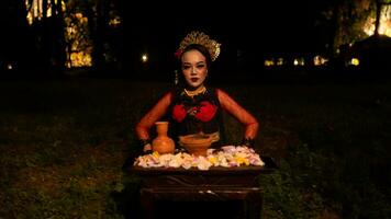 a female dancer looks focused on her ritual with a peaceful facial expression in front of offerings that look fresh and lively photo