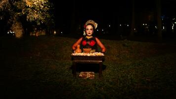 a female dancer looks focused on her ritual with a peaceful facial expression in front of offerings that look fresh and lively photo