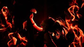 the silhouette of a female dancer holding jewelry shines brightly around the flames and looks bold in the dark photo