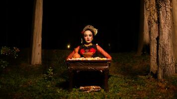 a female dancer looks focused on her ritual with a peaceful facial expression in front of offerings that look fresh and lively photo