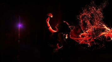 the silhouette of a female dancer holding sparkling jewelry and looking sharp in the dark with fire burning in the background photo