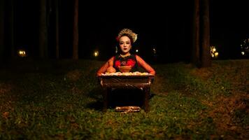 a female dancer looks focused on her ritual with a peaceful facial expression in front of offerings that look fresh and lively photo