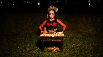 a female dancer looks focused on her ritual with a peaceful facial expression in front of offerings that look fresh and lively photo