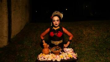 un hembra bailarín realiza un ritual ese crea un mágico y místico atmósfera en frente de flor ofrendas foto