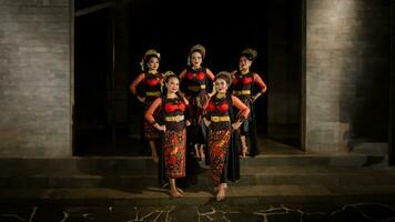 a group of dancers stand and unite in red costumes that show unity photo