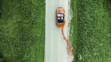 Aerial survey of red cabrioled goes on the road and couple using colored smoke.Flying over classic red convertible car traveling in the countryside at sunset with colored smoke. Lovers in the car photo