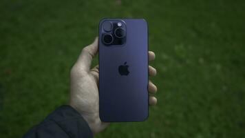 China, Beijing - September 15, 2023. New iPhone model 15 pro. Action. Hand holds new model of stylish iPhone 15 pro. Man holds new iPhone 15 pro on background of green grass photo