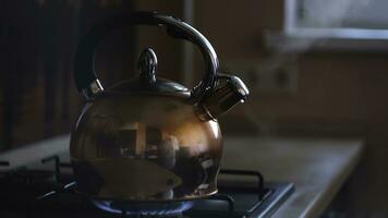 cerca arriba de humeante té pava. concepto. calentador brillante debajo el acero pulido tetera con hirviendo agua y el reflexión de el cocina en sus superficie. foto