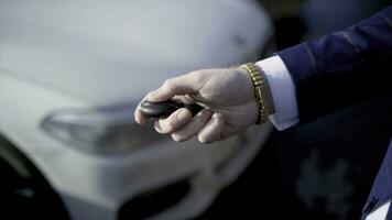 Close-up of businessman pressing car key. Action. Businessman opens car with electronic key and looks at phone. Modern car key to open and start it photo