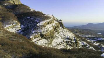 Beautiful mountain panorama with rock ledges and snow. Shot. Rock with small amount of snow on background of mountain panorama on sunny day photo