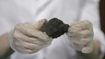 Male hands in gloves holding coal. Scientist with a sample of coal. Black coal in miner's hand photo