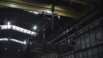 Frame of train on plant. Clip. Platform with train wheels is suspended on chains in factory. Frame of train with wheels hanging on chains at factory photo