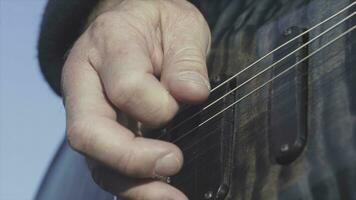 Close-up of hands playing bass guitar. Stock. Male hands of guitarist playing chords on bass guitar. Music performed on guitar photo