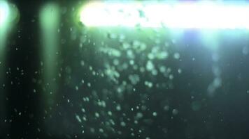 Side view of bubbling water with a green lamp on the background. Frame. Air bubbles underwater in empty fish aquarium. photo