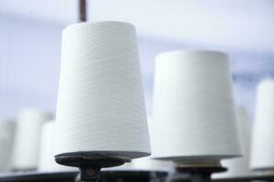 White Cotton Spools of Thread on the industrial knitting factory machine stand photo