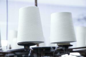 White Cotton Spools of Thread on the industrial knitting factory machine stand photo