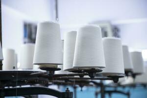 White Cotton Spools of Thread on the industrial knitting factory machine stand photo