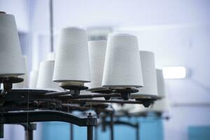 White Cotton Spools of Thread on the industrial knitting factory machine stand photo