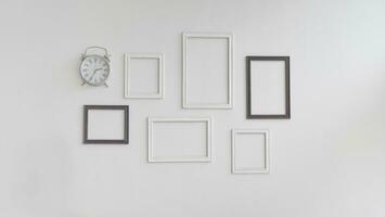 Multiple blank picture frames and clock on white wall background. photo