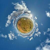 green tiny planet in blue sky with beautiful clouds. Transformation of spherical panorama 360 degrees. Spherical abstract aerial view. Curvature of space. photo