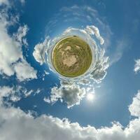 green tiny planet in blue sky with beautiful clouds. Transformation of spherical panorama 360 degrees. Spherical abstract aerial view. Curvature of space. photo