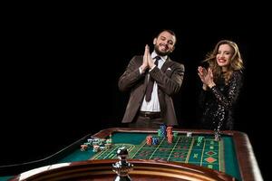 Man and woman playing at roulette table in casino photo