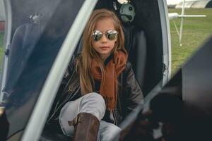 interpolación niña en reflejado Gafas de sol sentado en abierto helicóptero foto