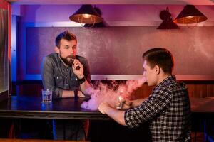 Vaping man holding a mod. A cloud of vapor at the vapebar. photo