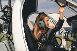 Focused preteen girl in pilot headset sitting in helicopter cockpit photo