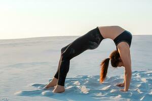 Fitness yoga woman stretching on sand. Fit female athlete doing yoga pose. photo